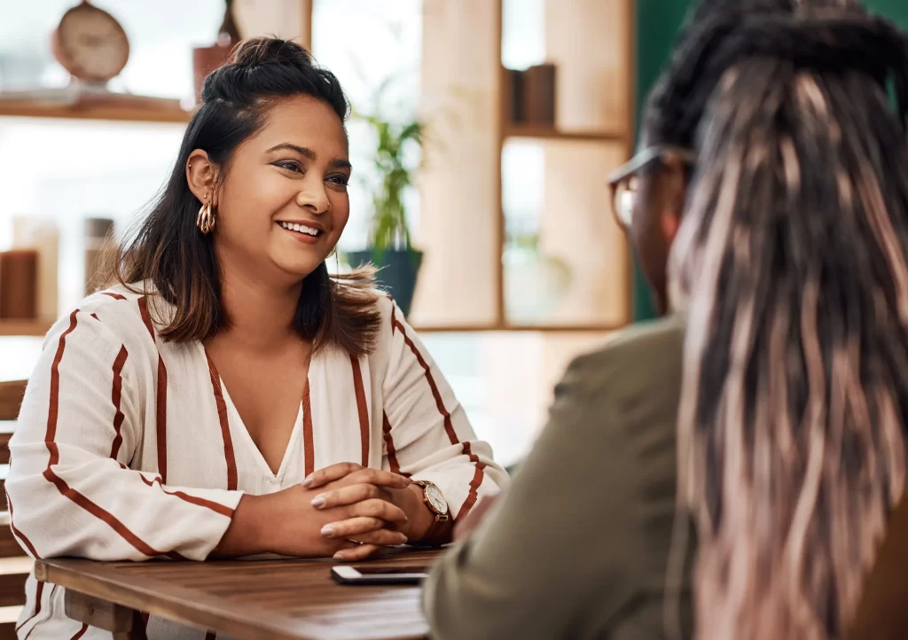 Latina woman smiling while communicating in a cafe.
